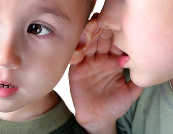 Zwei Kinder flüstern sich was ins Ohr